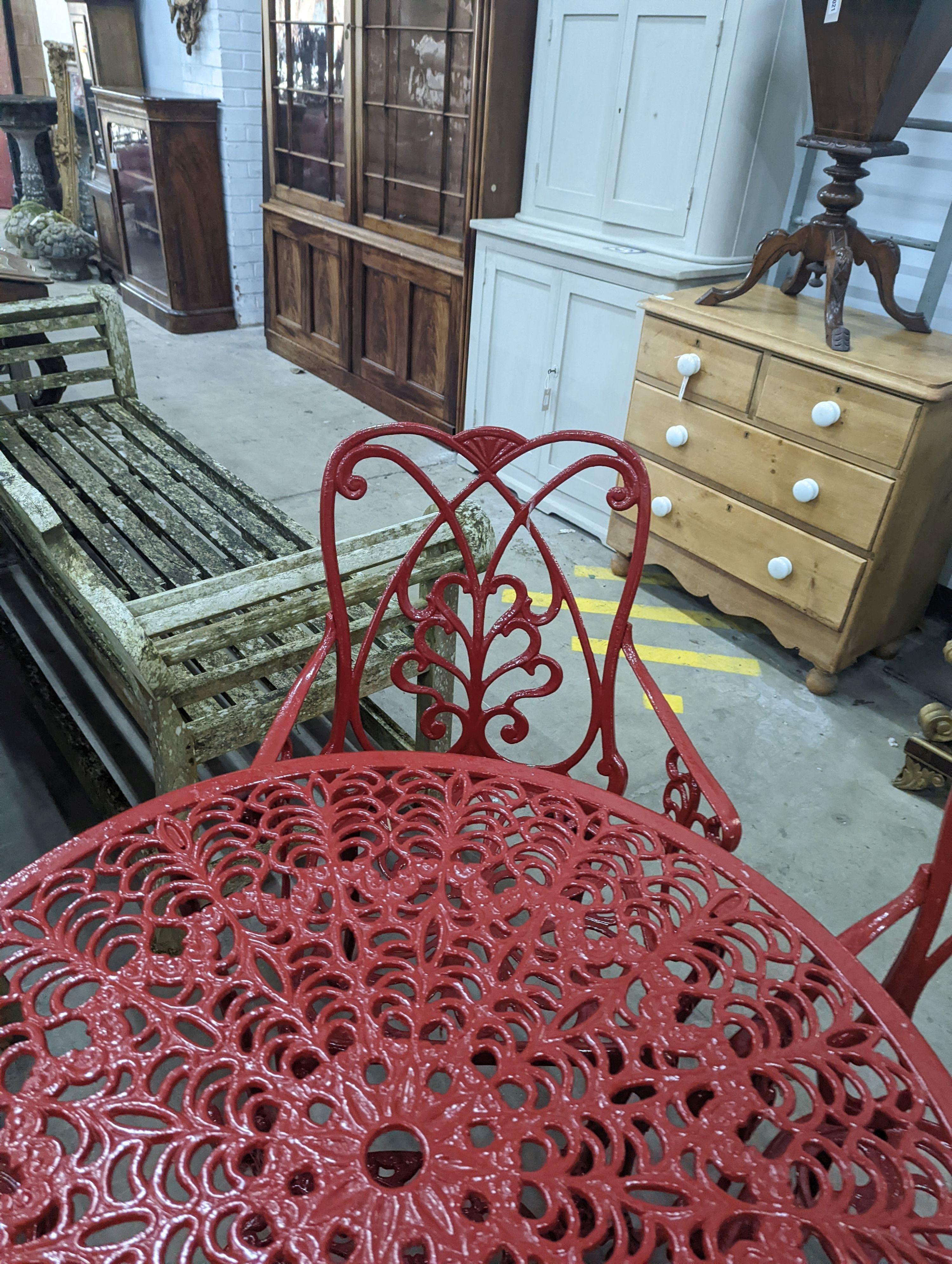 A circular red painted aluminium garden table, diameter 86cm, height 67cm together with four matching chairs